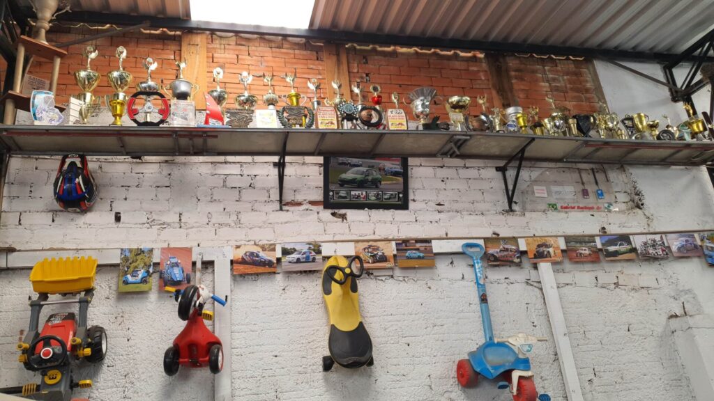 parede de tijolos e sem reboco com uma extensa prateleira cheia de troféus em diversos formatos